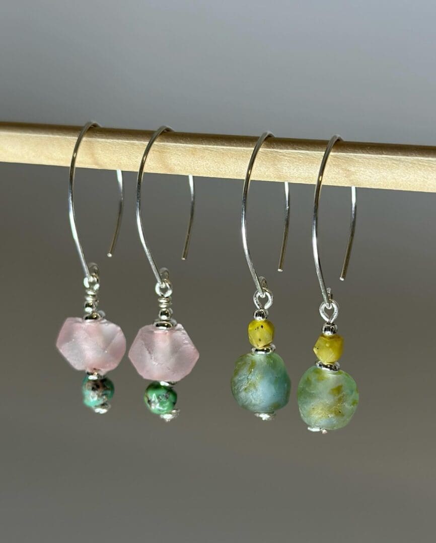 A pair of earrings hanging from a wooden stick.