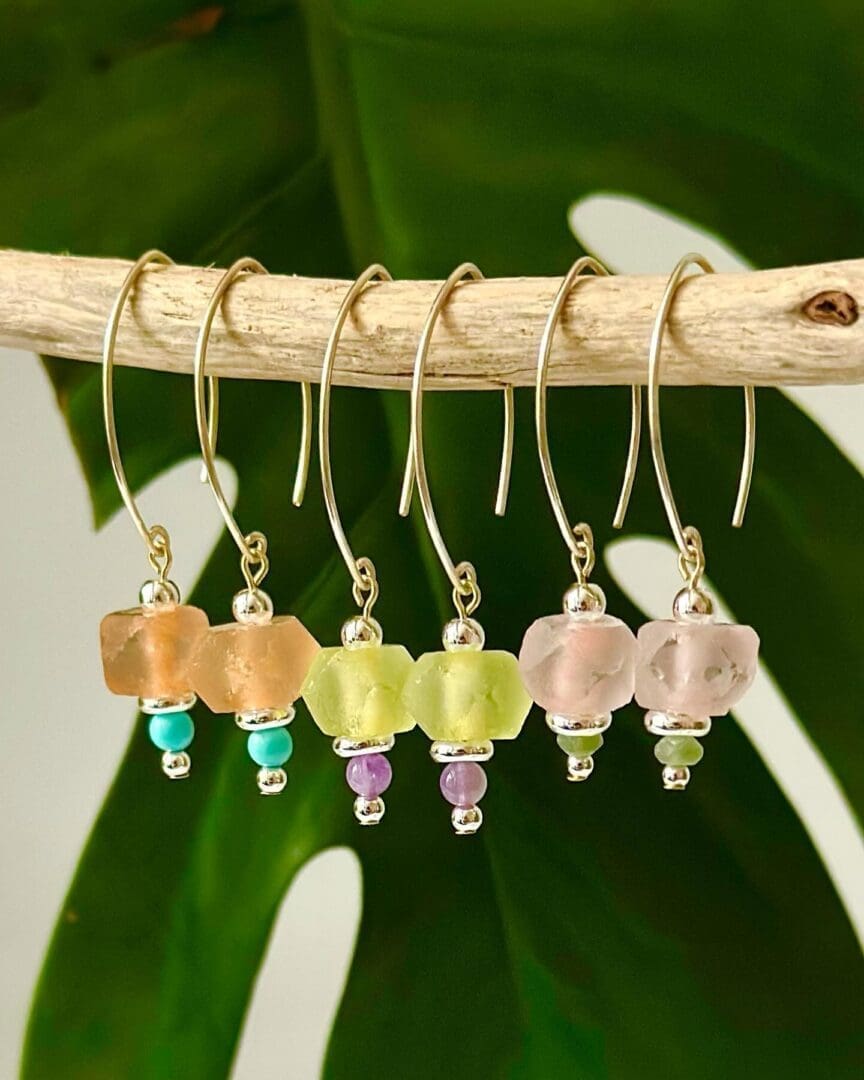 A group of six earrings hanging on a tree branch.