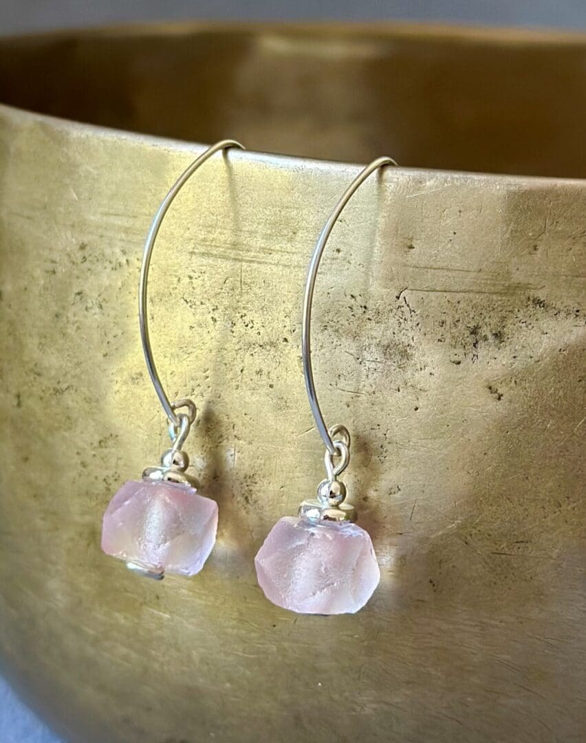 A pair of earrings with pink stones on them.