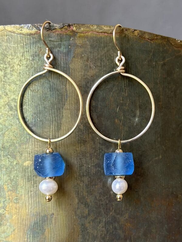 A pair of earrings with blue glass and pearls.