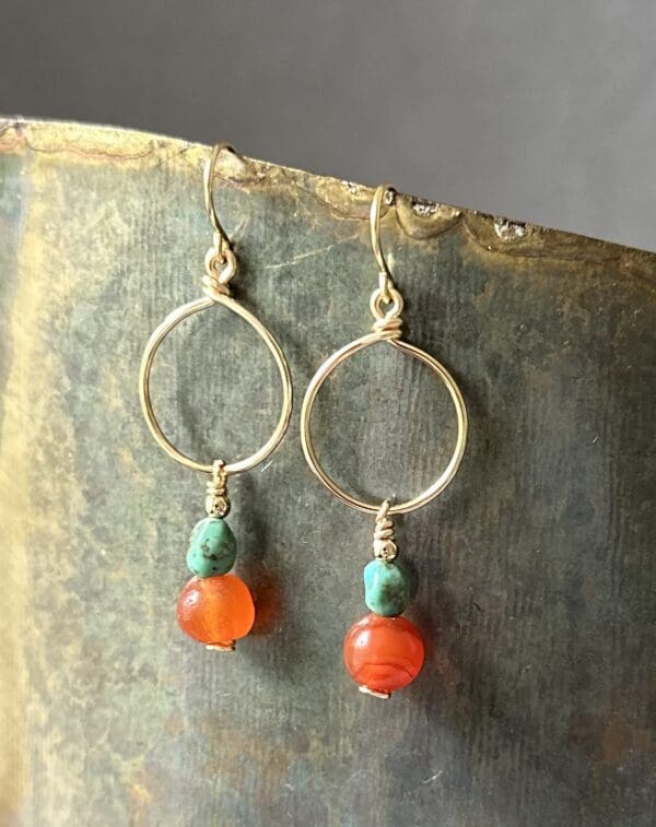 A pair of earrings with orange and turquoise beads.