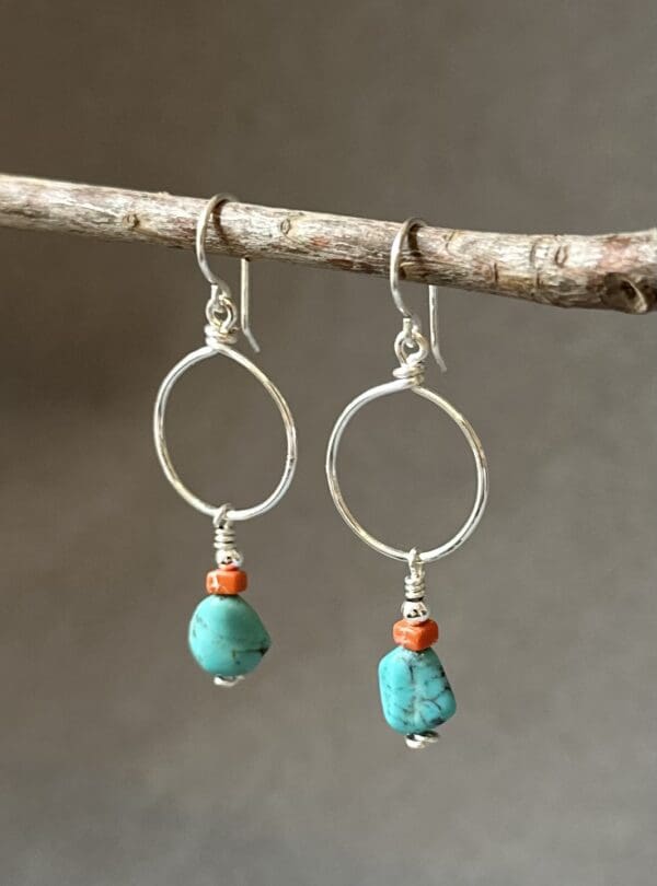 A pair of earrings hanging from a tree branch.