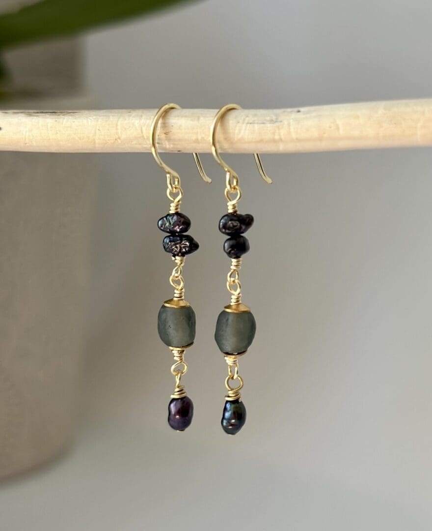 A pair of earrings hanging from a wooden stick.