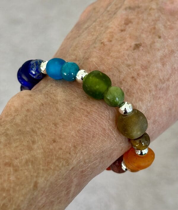 A person wearing a bracelet with different colored beads.