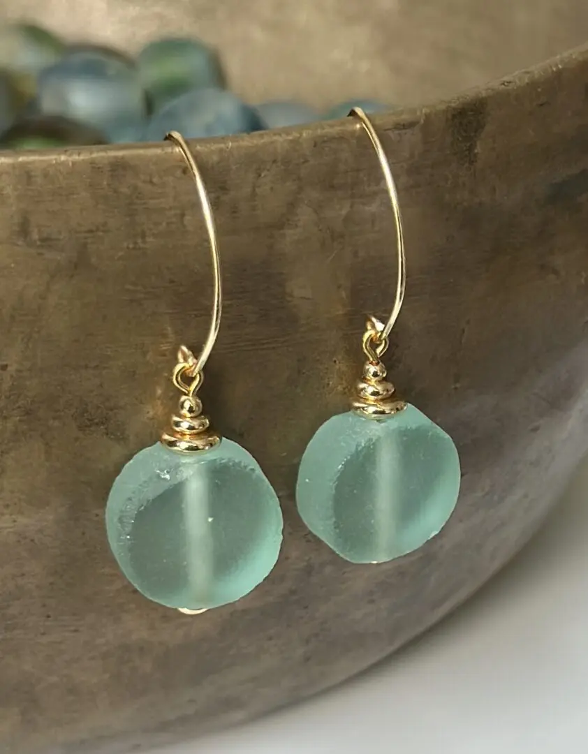 A pair of earrings sitting on top of a wooden bowl.