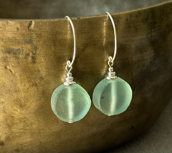 A pair of earrings sitting on top of a wooden bowl.