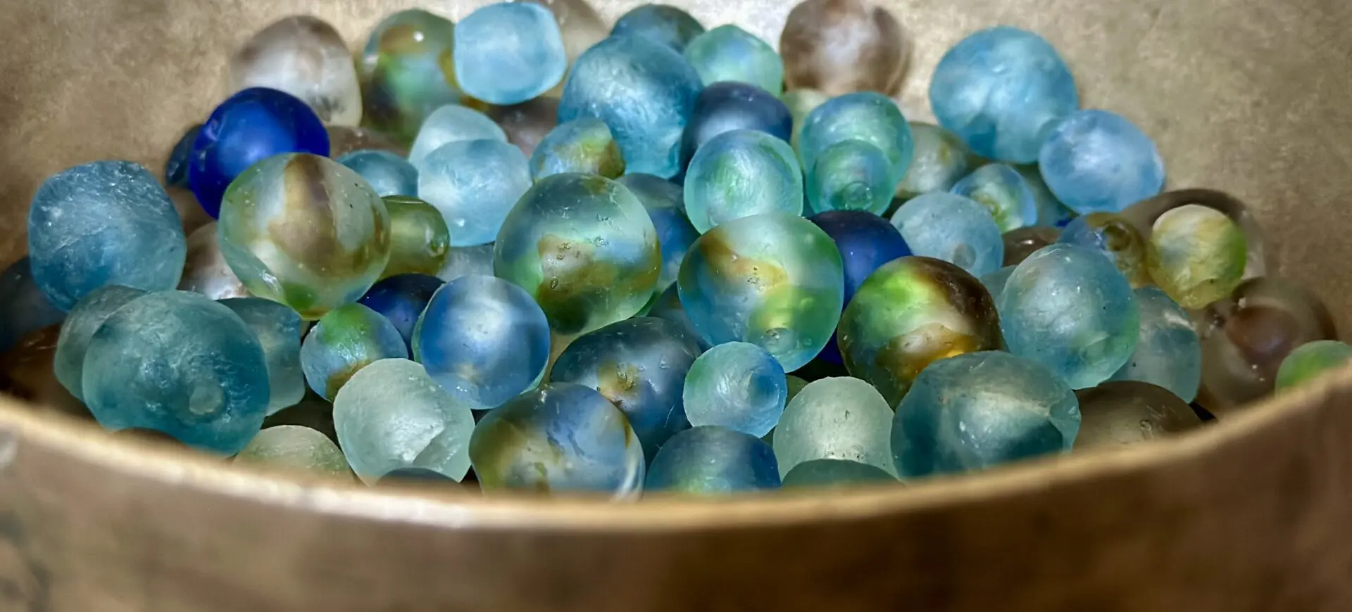 A bowl of blue and green glass beads.