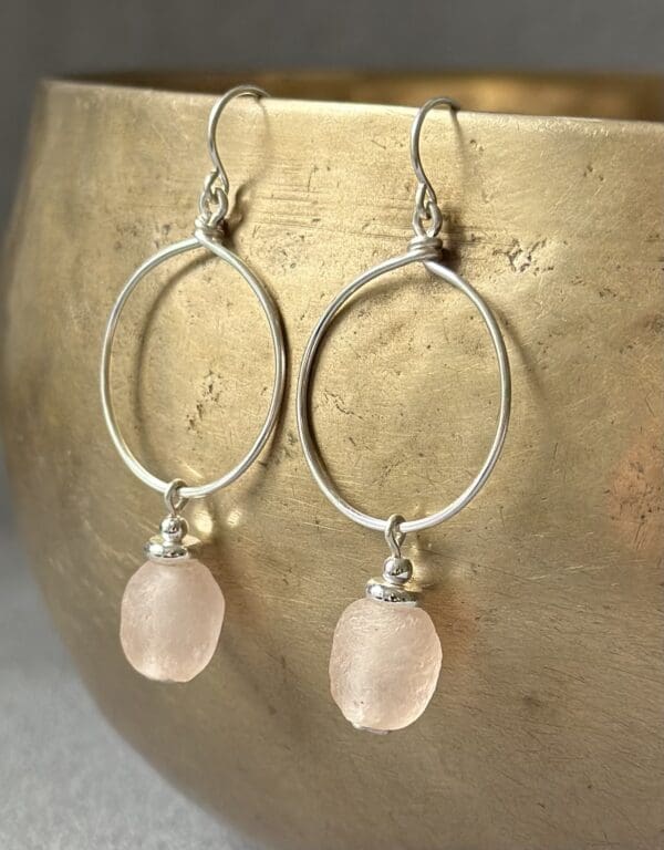 A pair of earrings with pink beads hanging from them.