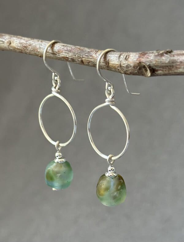 A pair of earrings hanging from a tree branch.