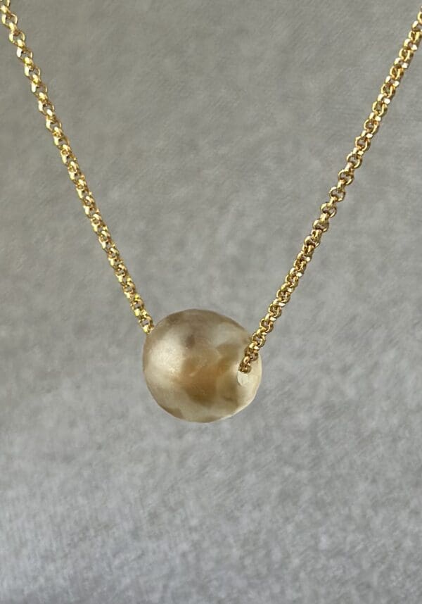 A gold necklace with a ball on it